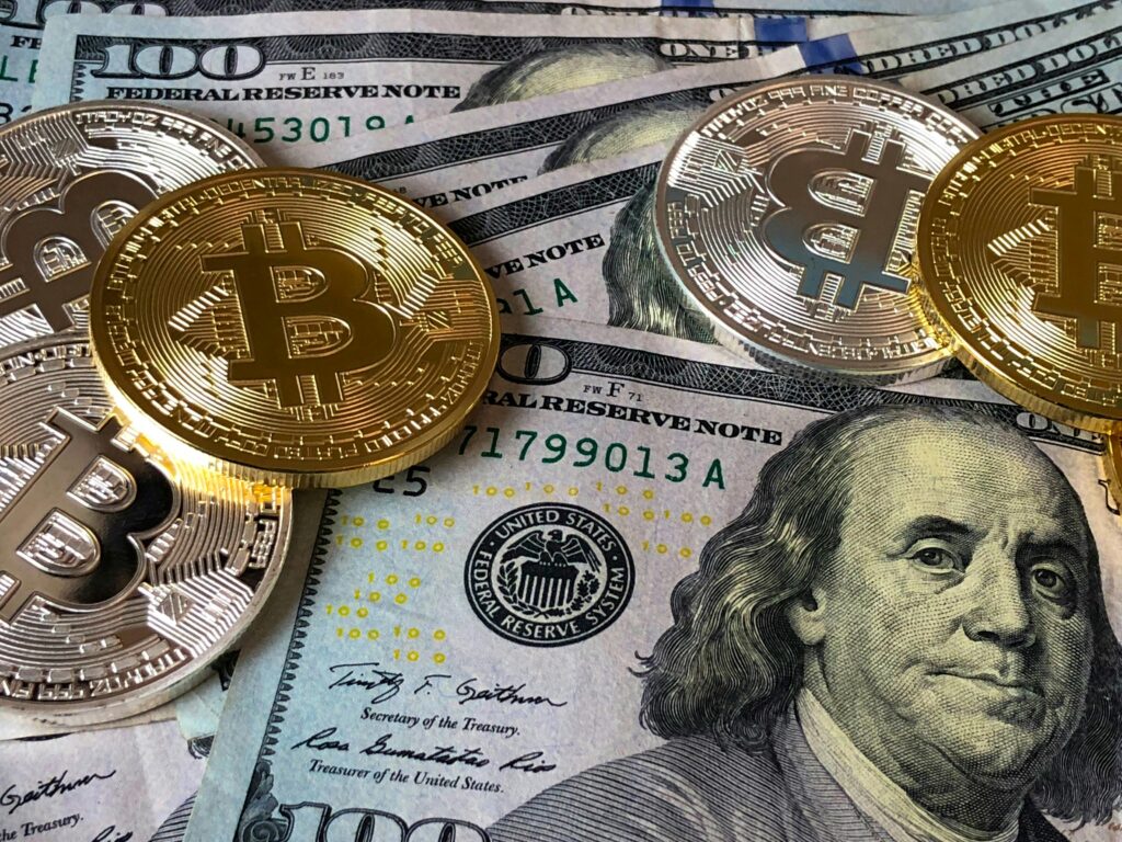 Gold and silver Bitcoin tokens on top of U.S. hundred-dollar bills